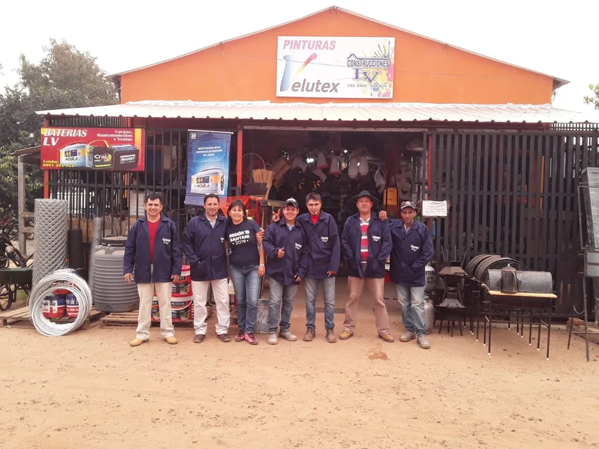 El equipo de LV con sus camperas azules frente al local naranja, con tanques, tejido, pinturas y parrillas en la vereda